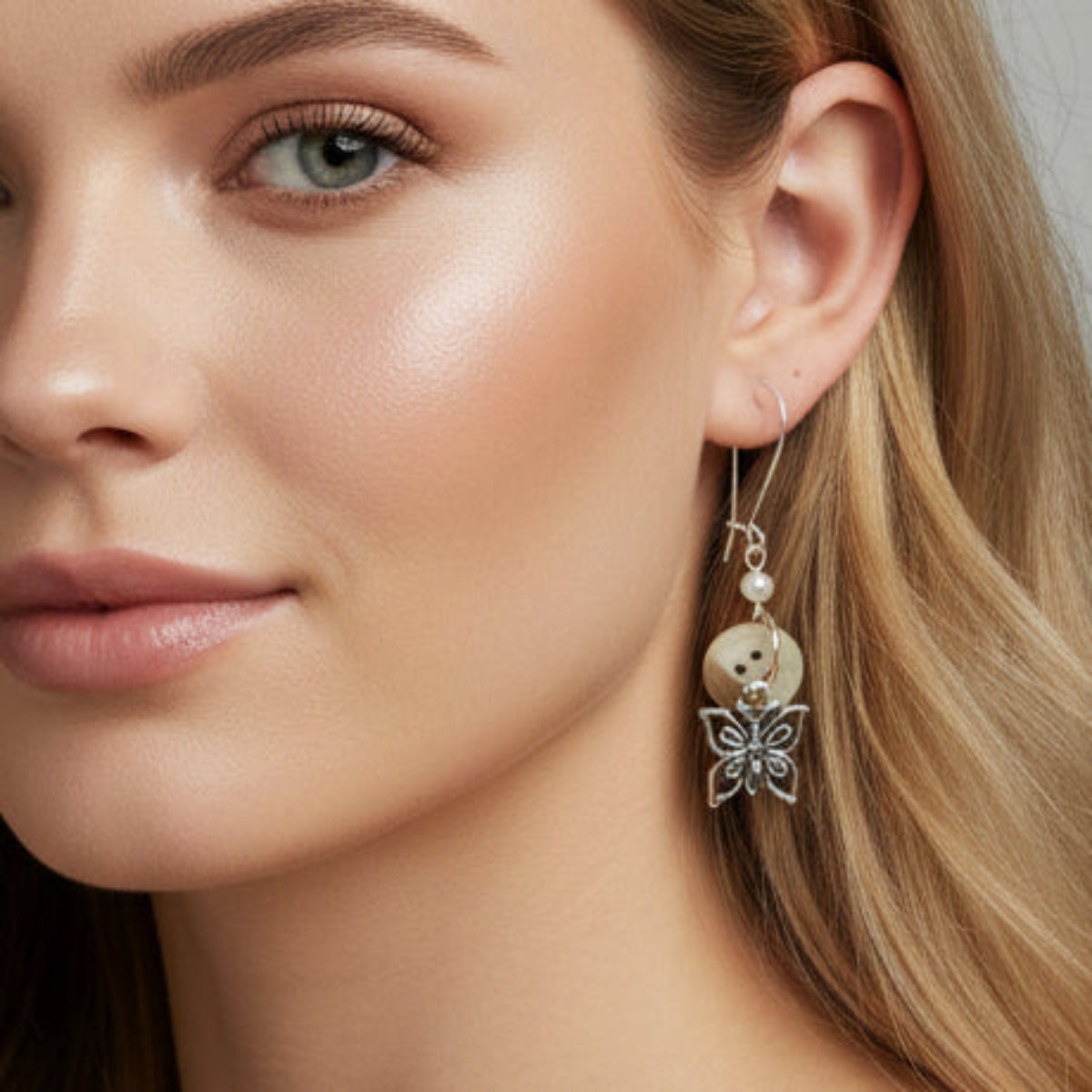 Butterfly-shaped earrings with silver hooks on a gray background