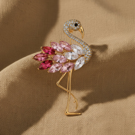 Flamingo-shaped brooch with gemstones held by a hand against a neutral background