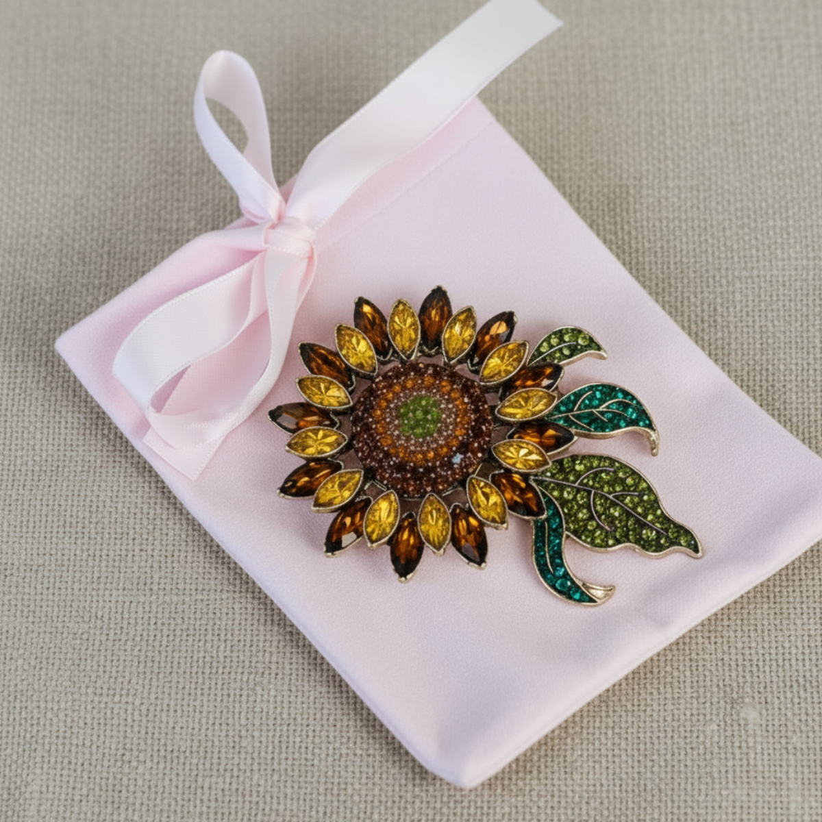 Sunflower-shaped brooch with gemstones on a pink satin bag against a beige background, Sunflower Crystal Brooch Pin 3x4" | Amber & Teal Rhinestone Brooch