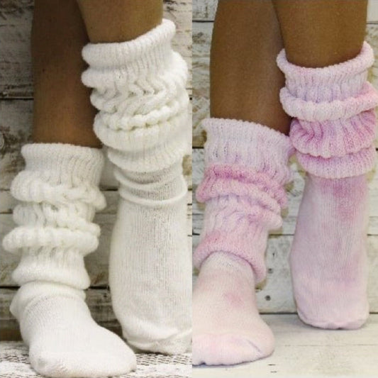 White and pink knitted leg warmers on feet against a wooden background