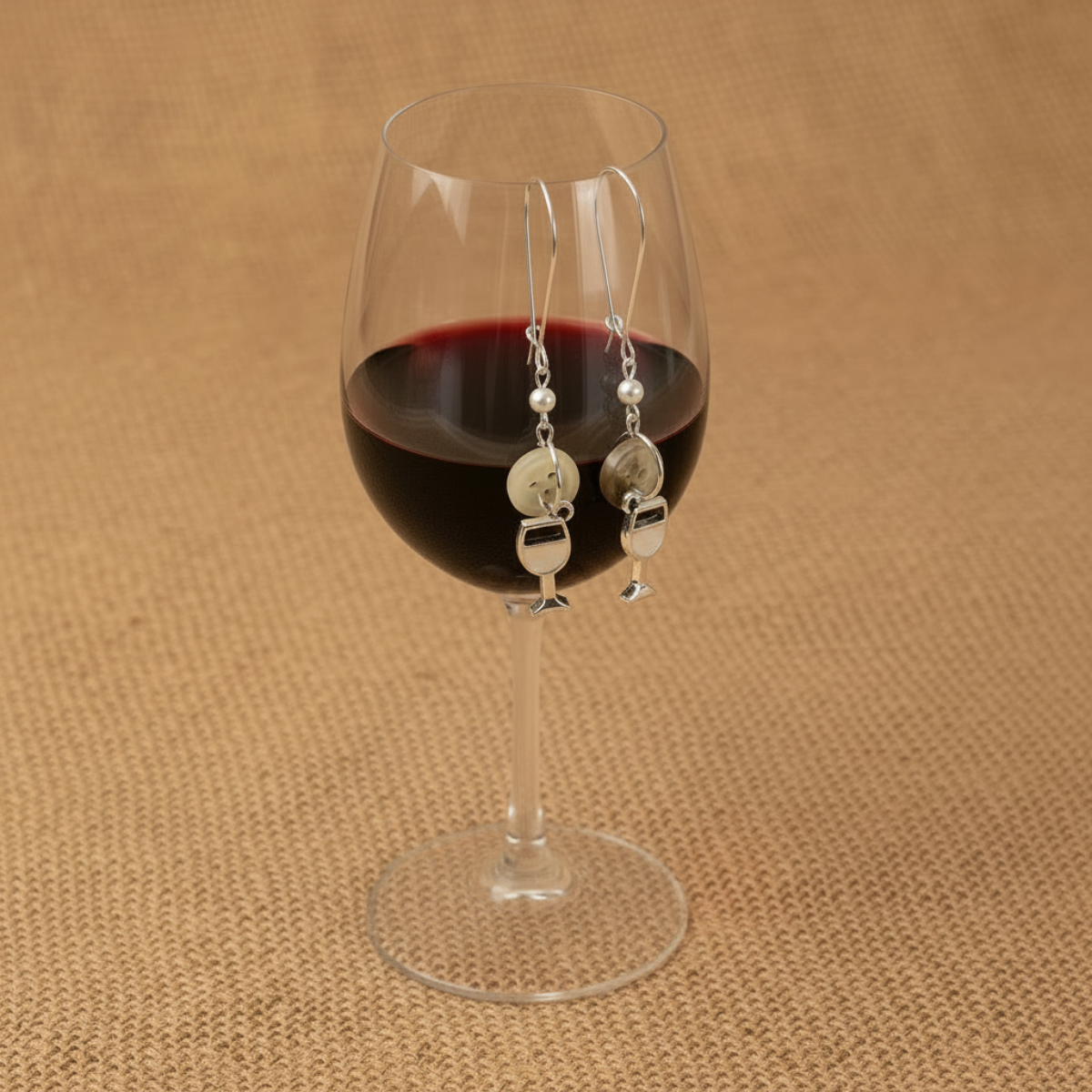 Wine glass with red wine and a pair of earrings on a brown textured background, wine glass earring set for girls night out