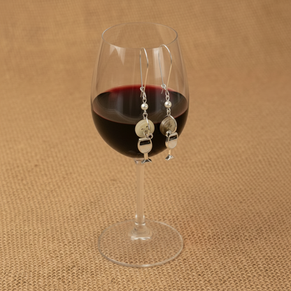 Wine glass with red wine and a pair of earrings on a brown textured background, wine glass earring set for girls night out